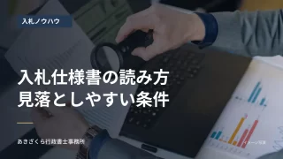パソコンと資料を虫眼鏡で確認する人の手元。入札仕様書の確認ポイントの見出し入り