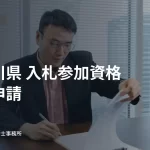 机で書類に記入する人。神奈川県の入札参加資格定期申請の見出し入り