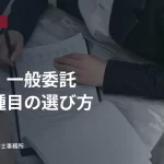 机を挟んで資料を確認する二人の手元。物品・一般委託の営業種目の選び方の見出し入り